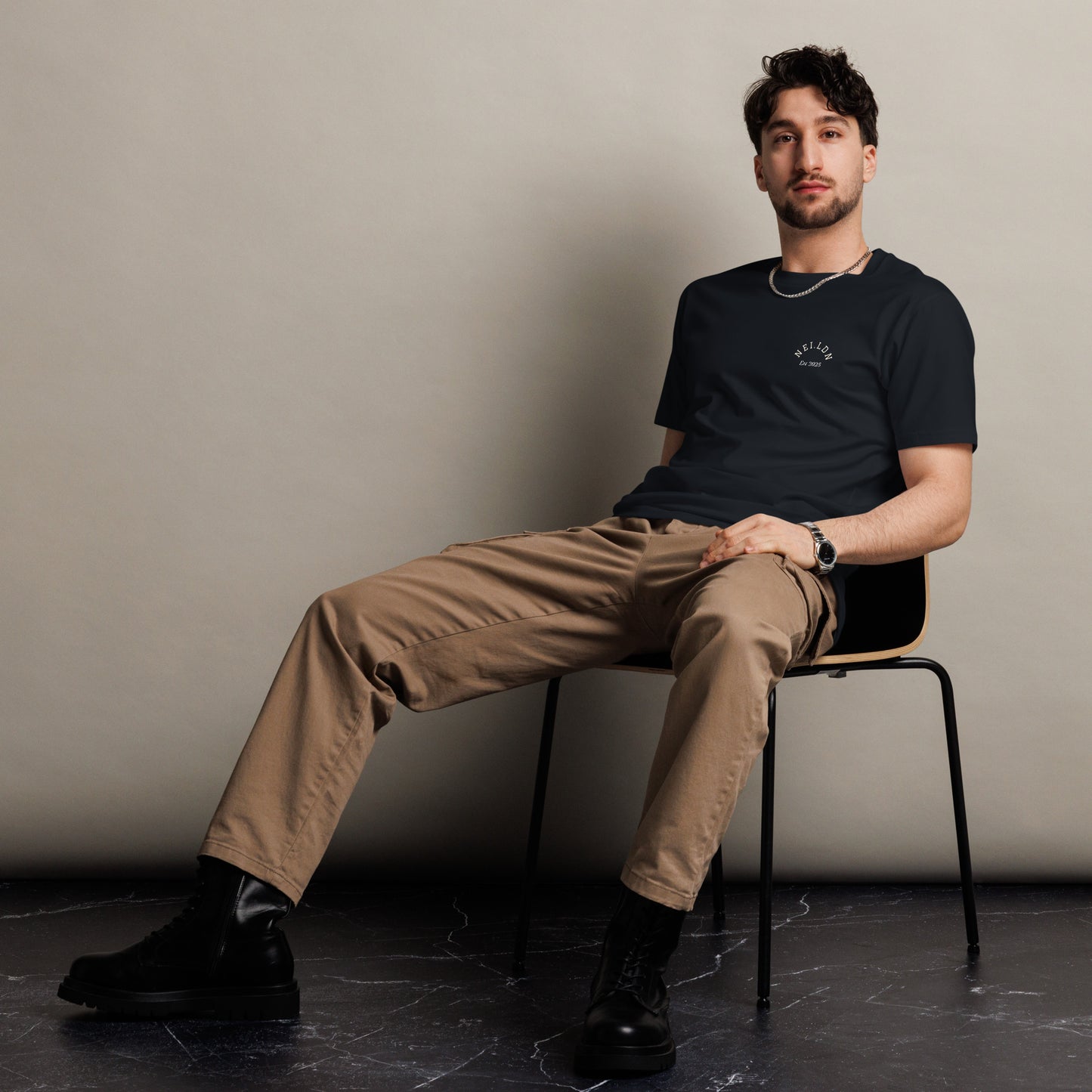 Model wearing Comfort Premium Navy T-Shirt seated on chair showcasing minimalist style