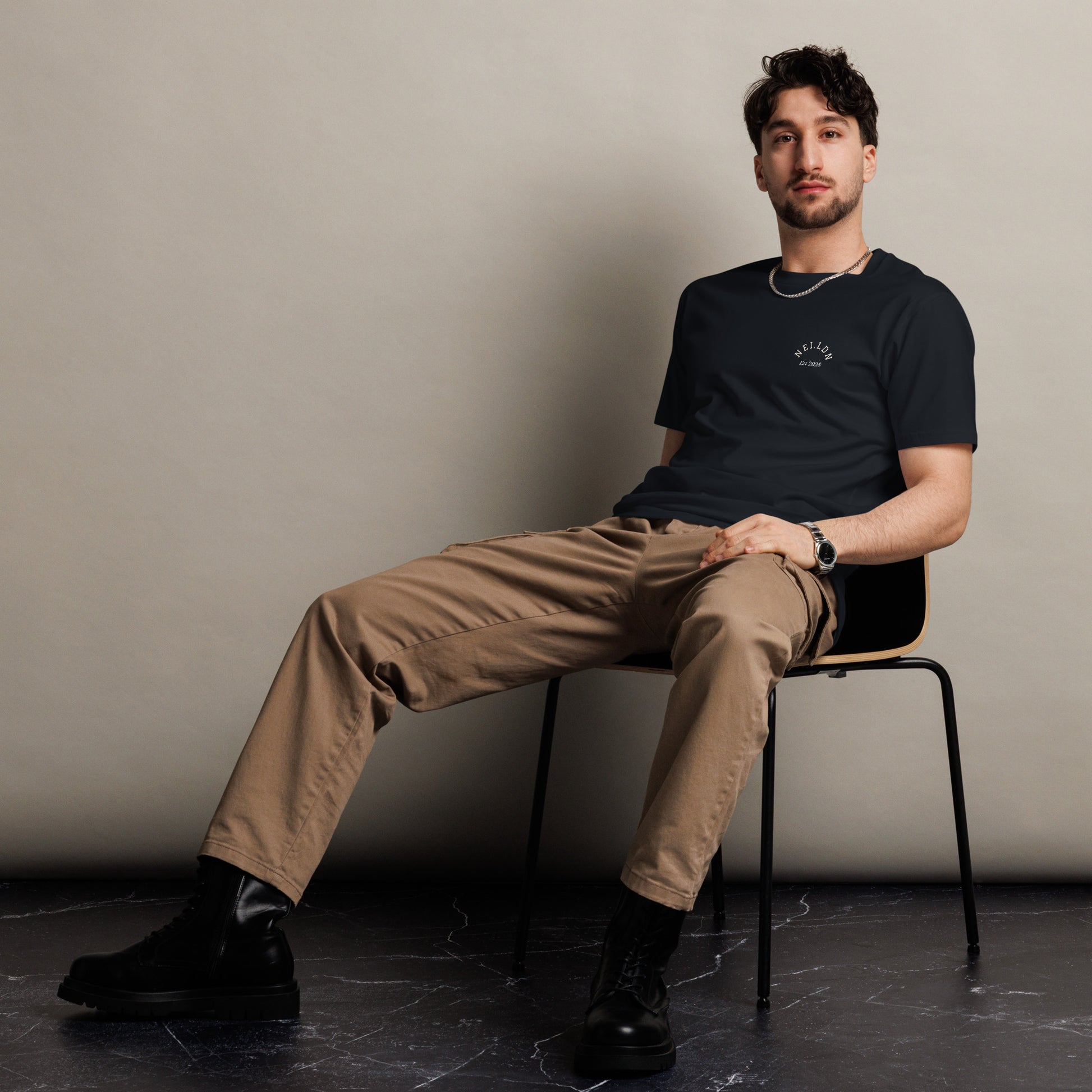 Model wearing Comfort Premium Navy T-Shirt seated on chair showcasing minimalist style